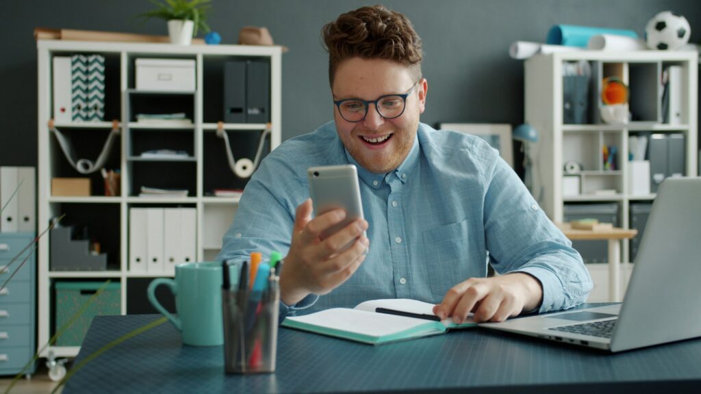 Smiling professional using a phone at an office desk